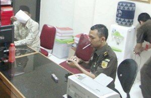 f-mantan Kepala DPPKD Provinsi Banten dan Staf Ahli Gubernur Banten Zaenal Mutaqin (kiri) menutupi wajahnya dengan kertas saat pelimpahan